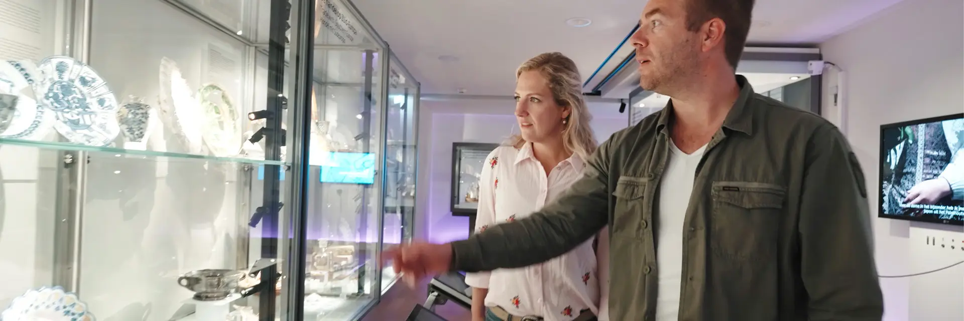 Man en vrouw kijken naar een vitrine met items in het Huis van Hilde