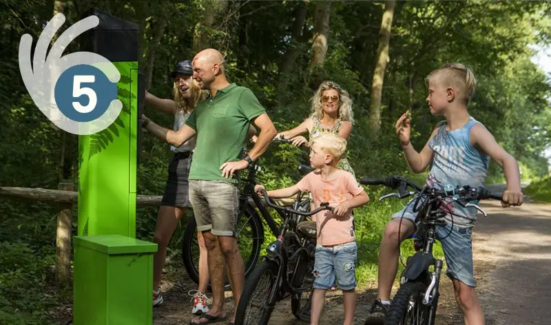 Familie staat bij een duinkaartapparaat
