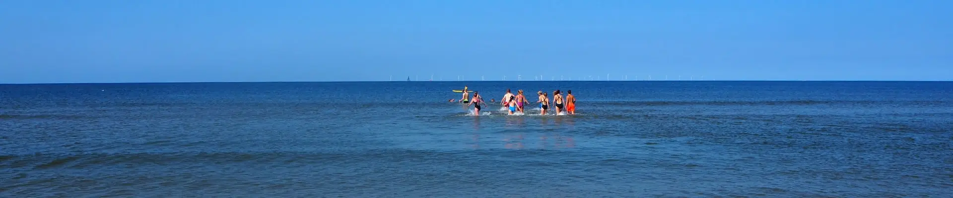 Groepje mensen rent de zee in.