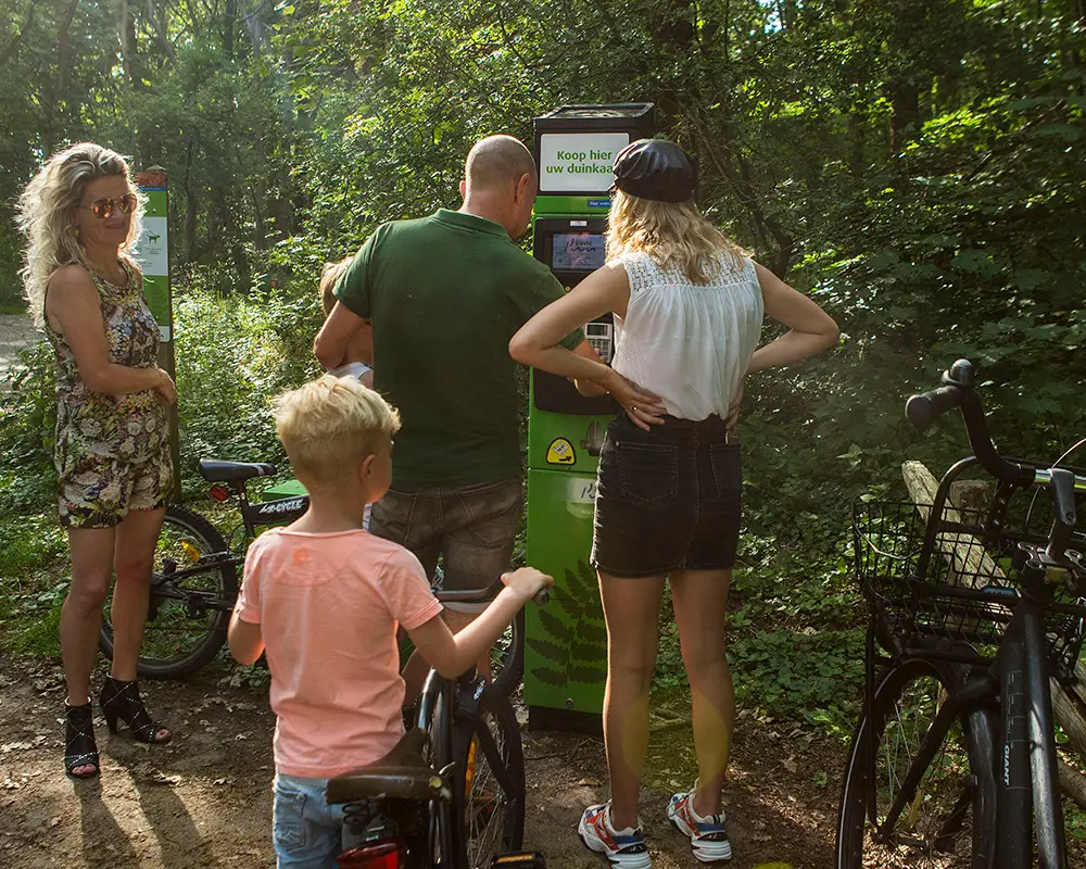 Gezin bij een duinkaartautomaat