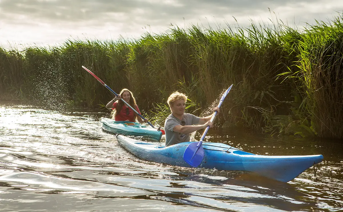 Meisje en jongen zijn aan het kanoën in alkersloot