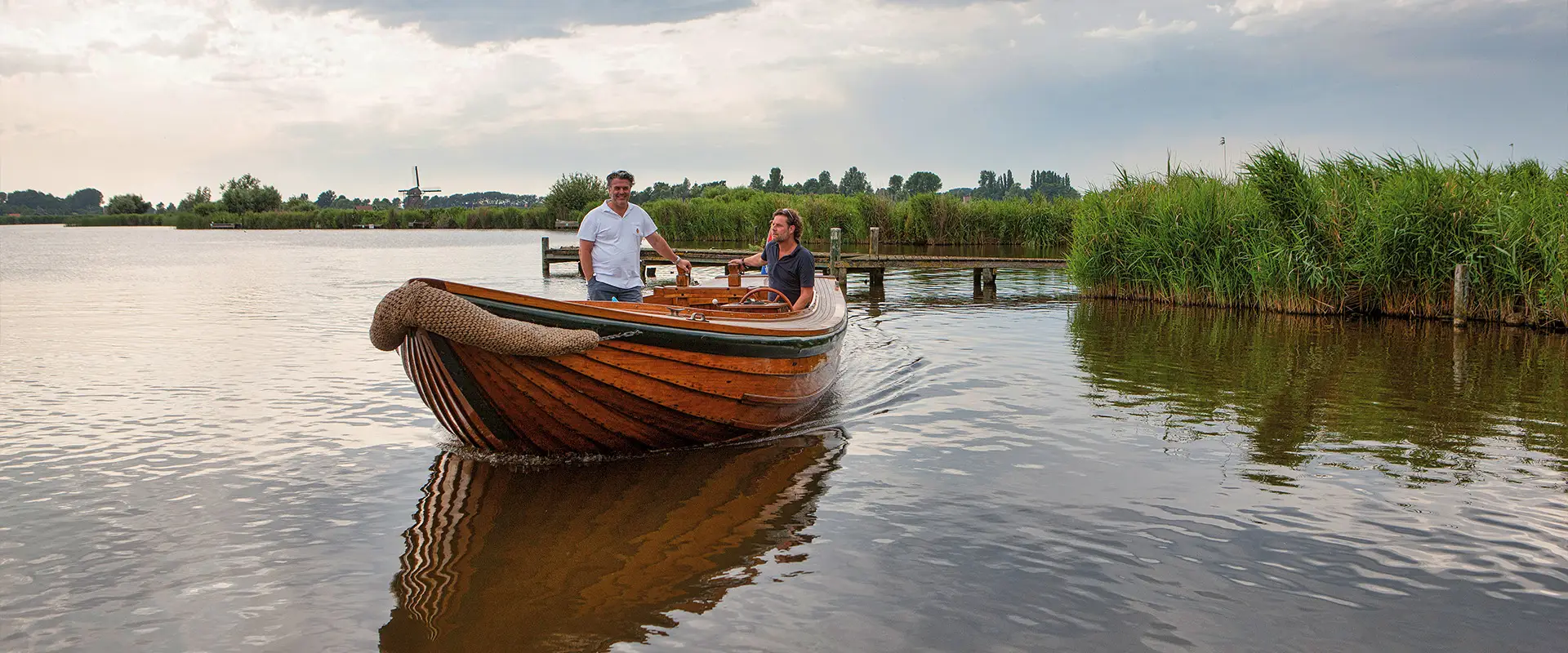 Houten sloep met twee mannen varend op het meer