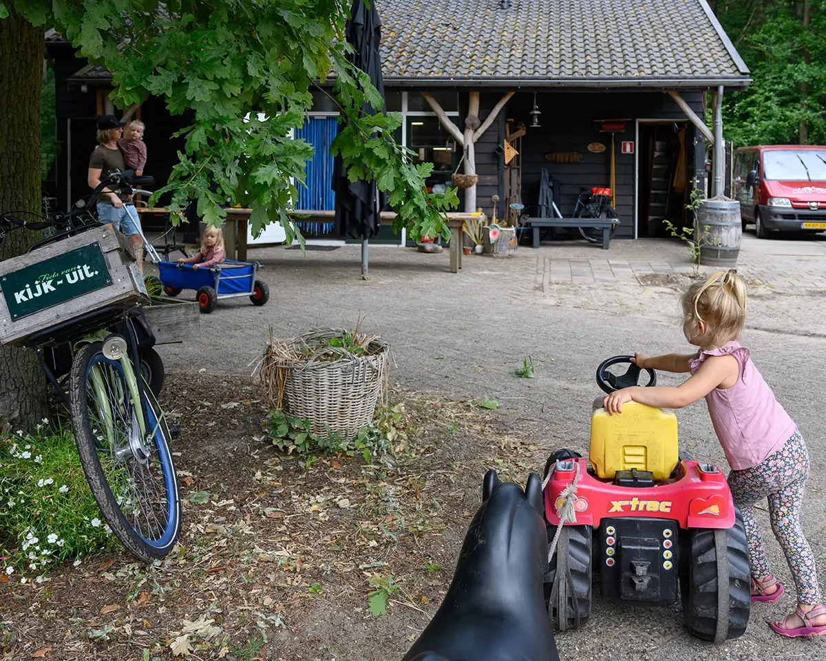 Meisje speelt met traktor buiten bij Hof van Kijk-Uit