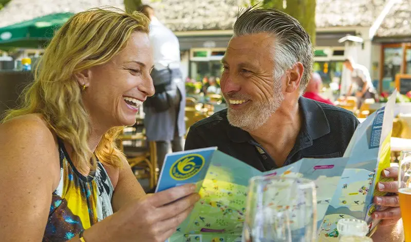 Stel op een terras die naar een plattegrond van Castricum kijkt