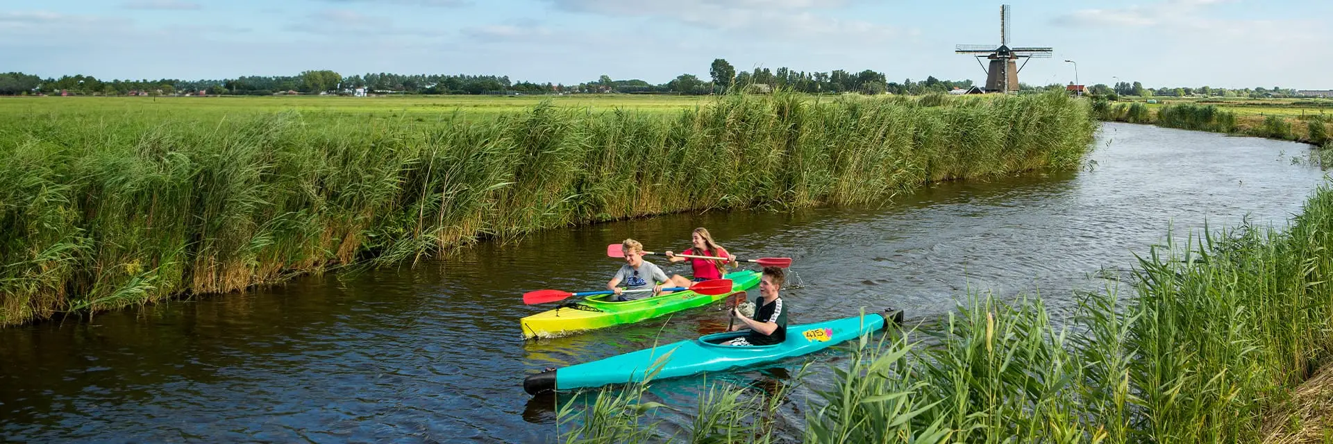 Drie kano's met een molen op de achtergrond