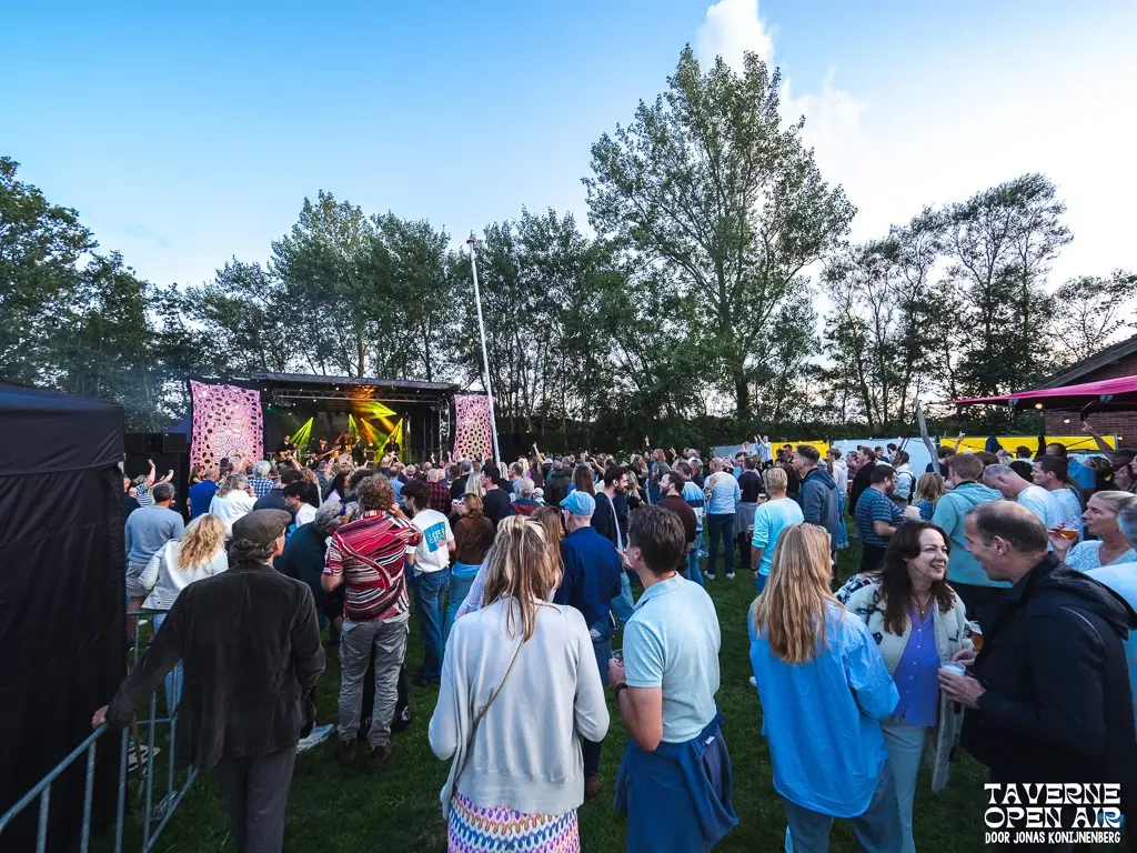 podium bij taverne open air en bergen met publiek die luistert naar het optreden