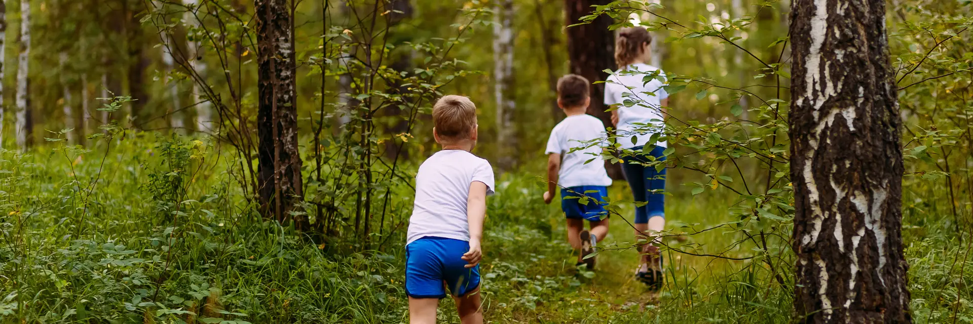 drie kinderen die door het bos rennen