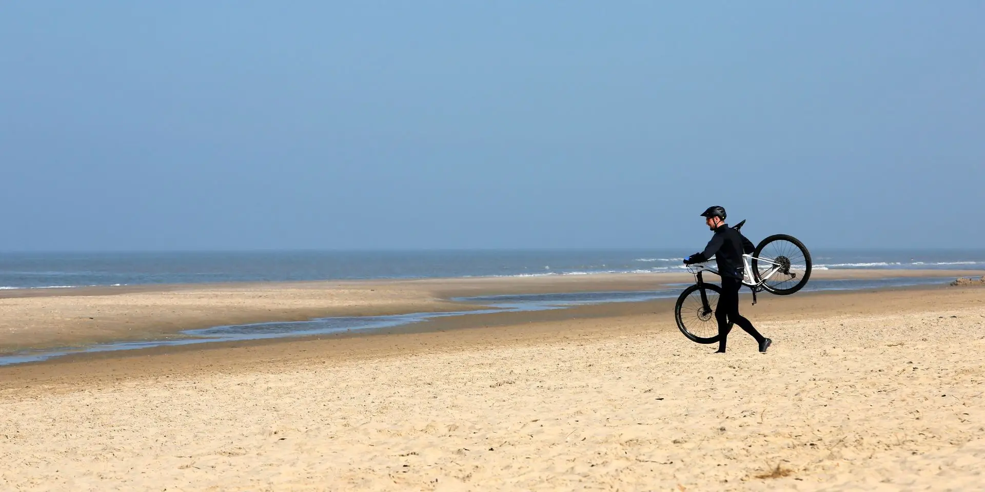 Fietser met mountainbike op het strand met zee uitzicht