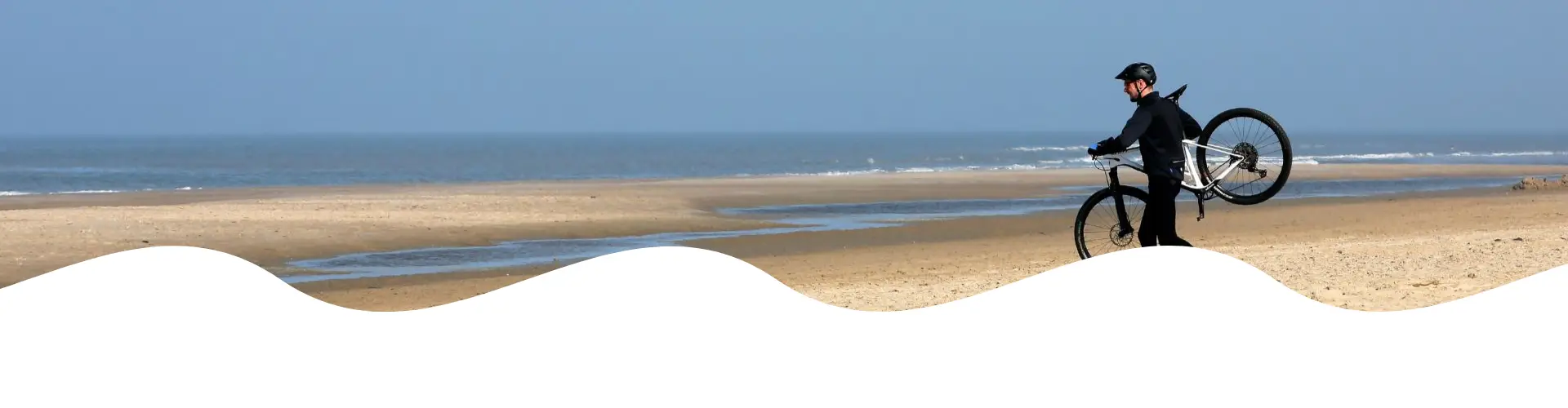 Fietser met mountainbike op het strand met zee uitzicht