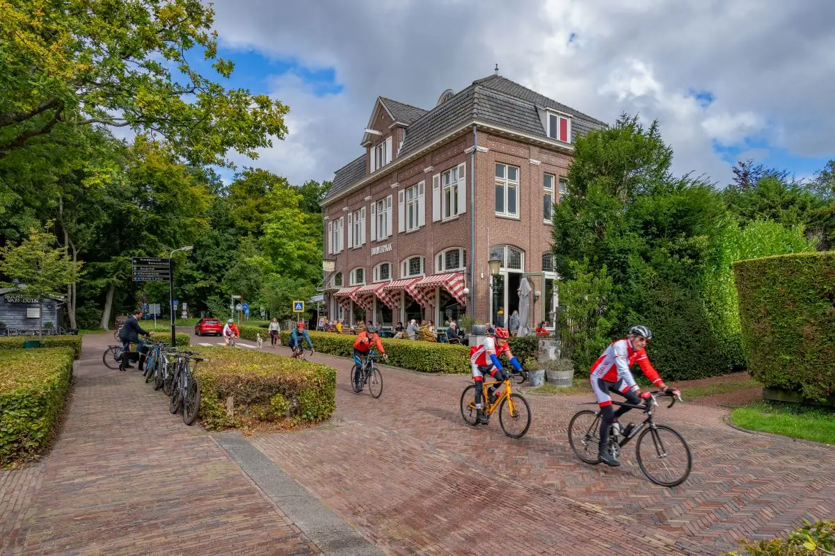 Foto van wielrenners langs een villa
