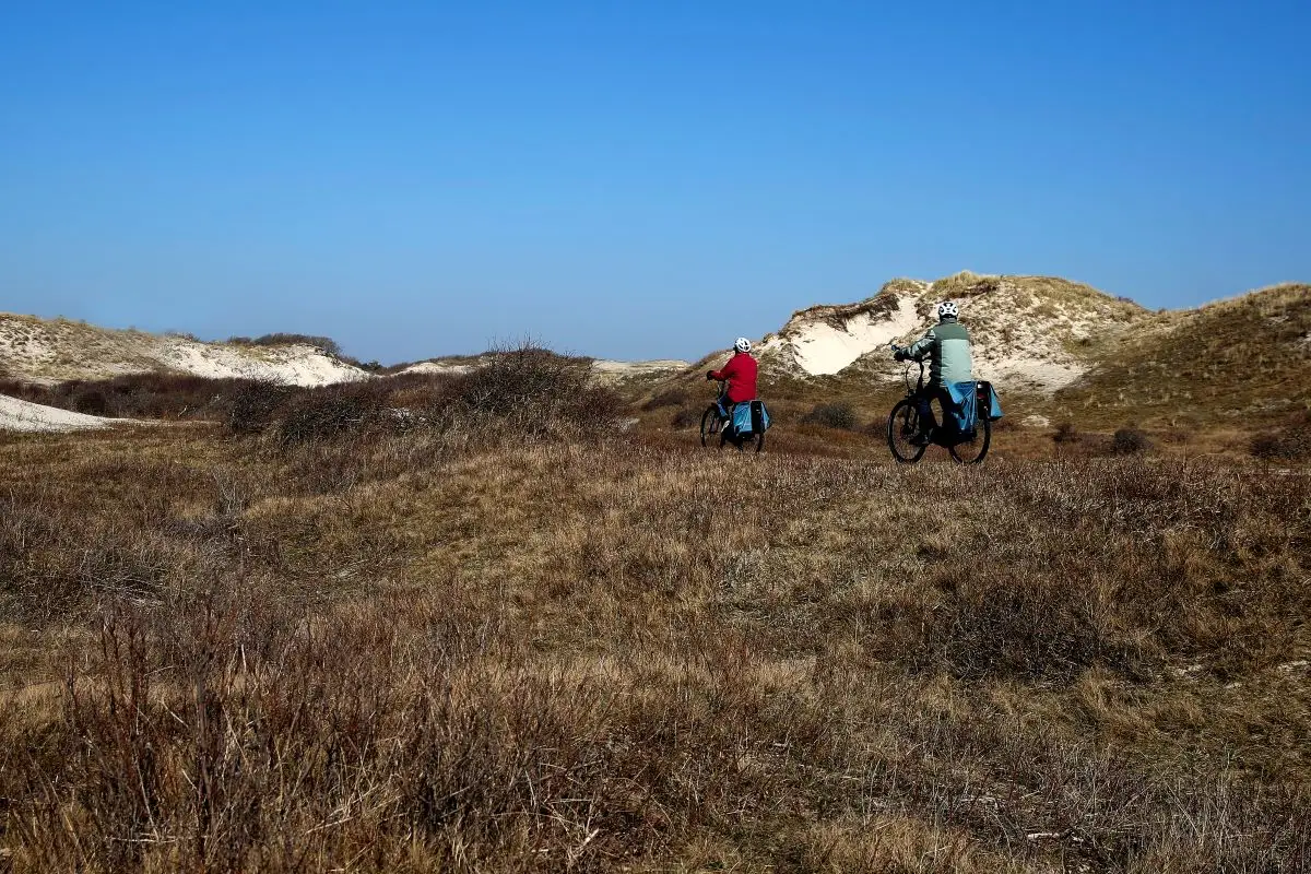 twee fietsers die door de duinen fietsen op het fietspad