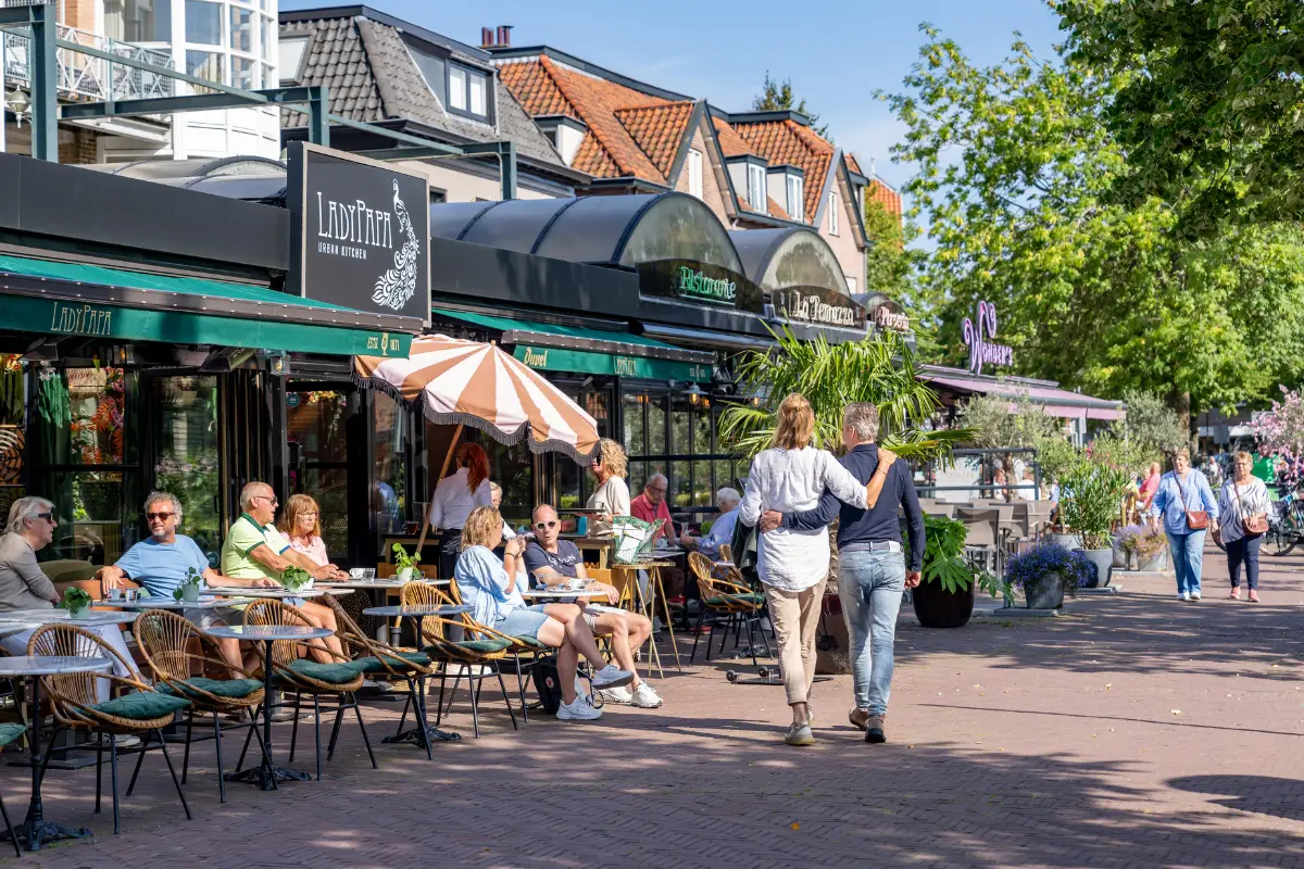 Zu Fuß Paar und Menschen auf der Terrasse in der Sonne im Zentrum von Bergen