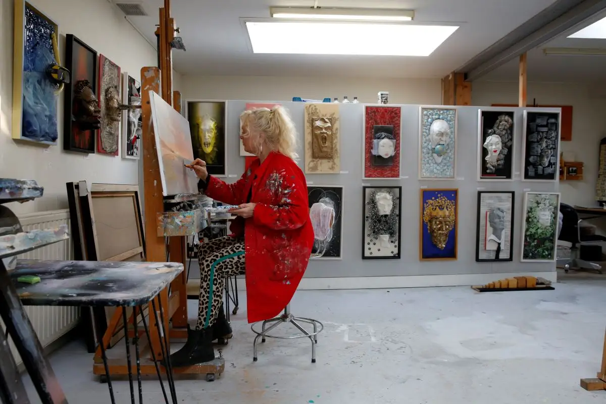 Een schilderende kunstenares in haar atelier, omringd door schilderijen