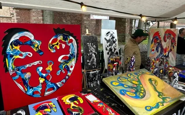 Kraam bij de kunstmarkt in Bergen met kleurrijke schilderijen