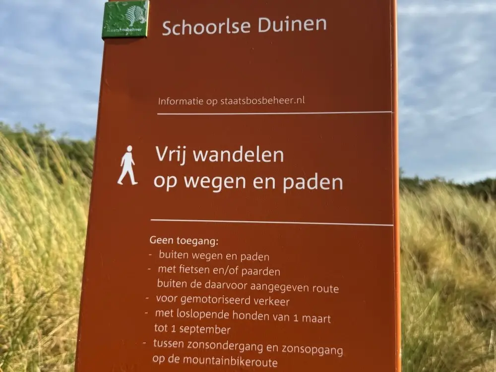 Bruin bord met regels van de Schoorlse Duinen over wandelen van Staatsbosbeheer