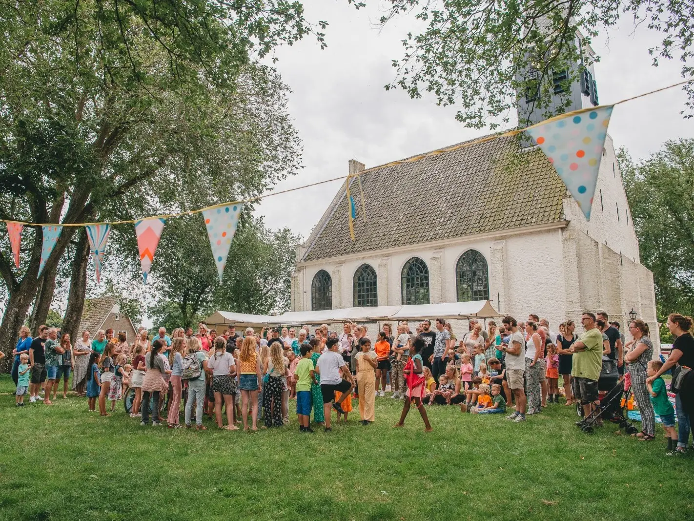 Zomergroet met kraampjes met op de achtergrond de witte kerk in Groet