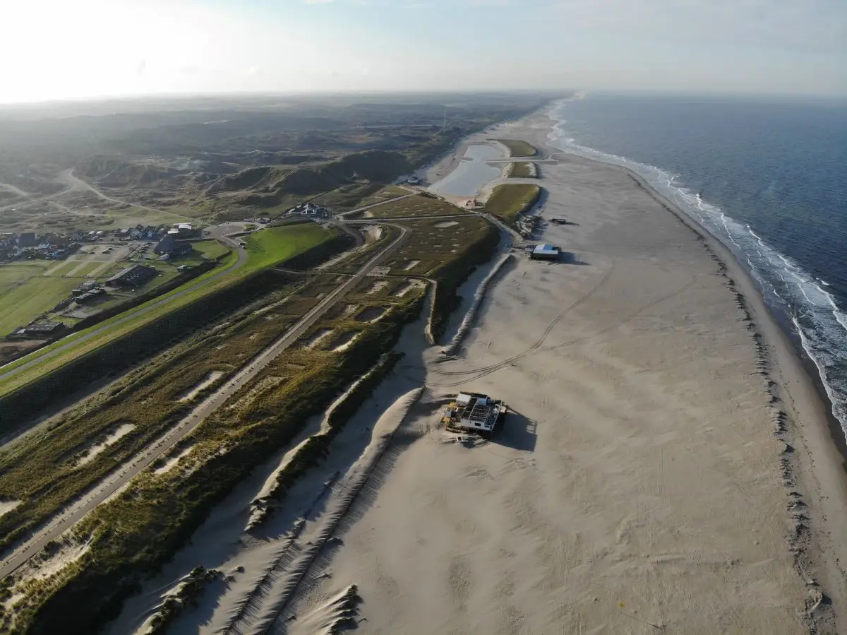 Bovenaanzicht van de kustlijn bij Camperduin met het strand, de polder, de duinen en de zee met strandpaviljoens