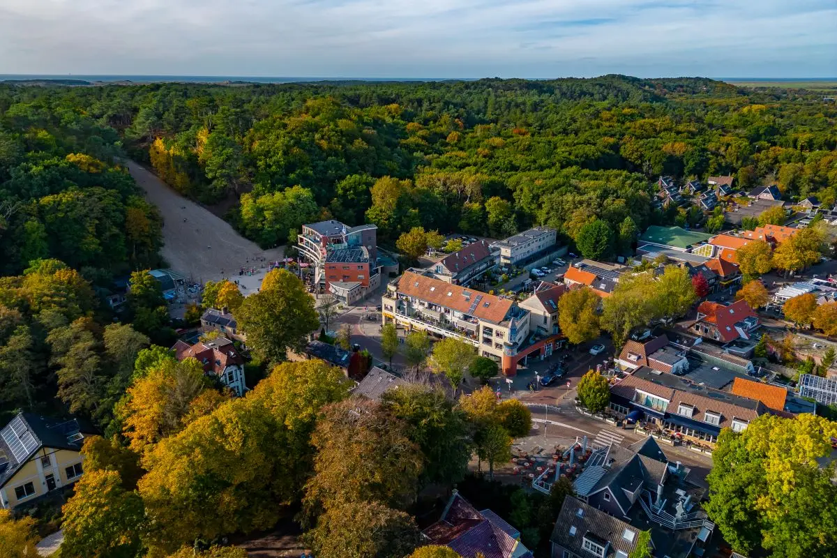 Luchtfoto van het centrum van Schoorl met Klimduin en de bossen in herfsttinten