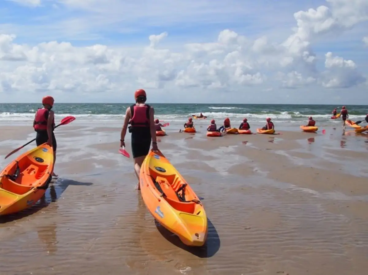 groep mensen die de kajak naar de zee tillen