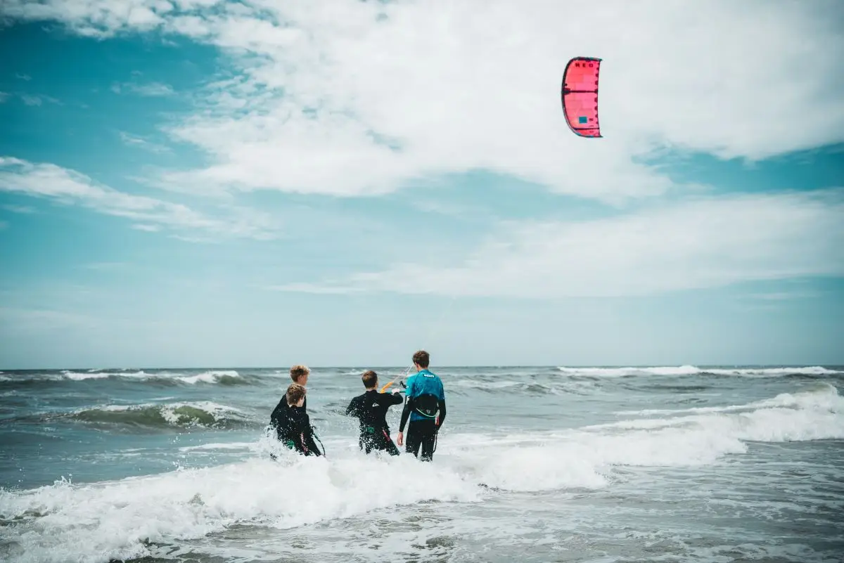 3 jongens die aan het kitesurfen zijn