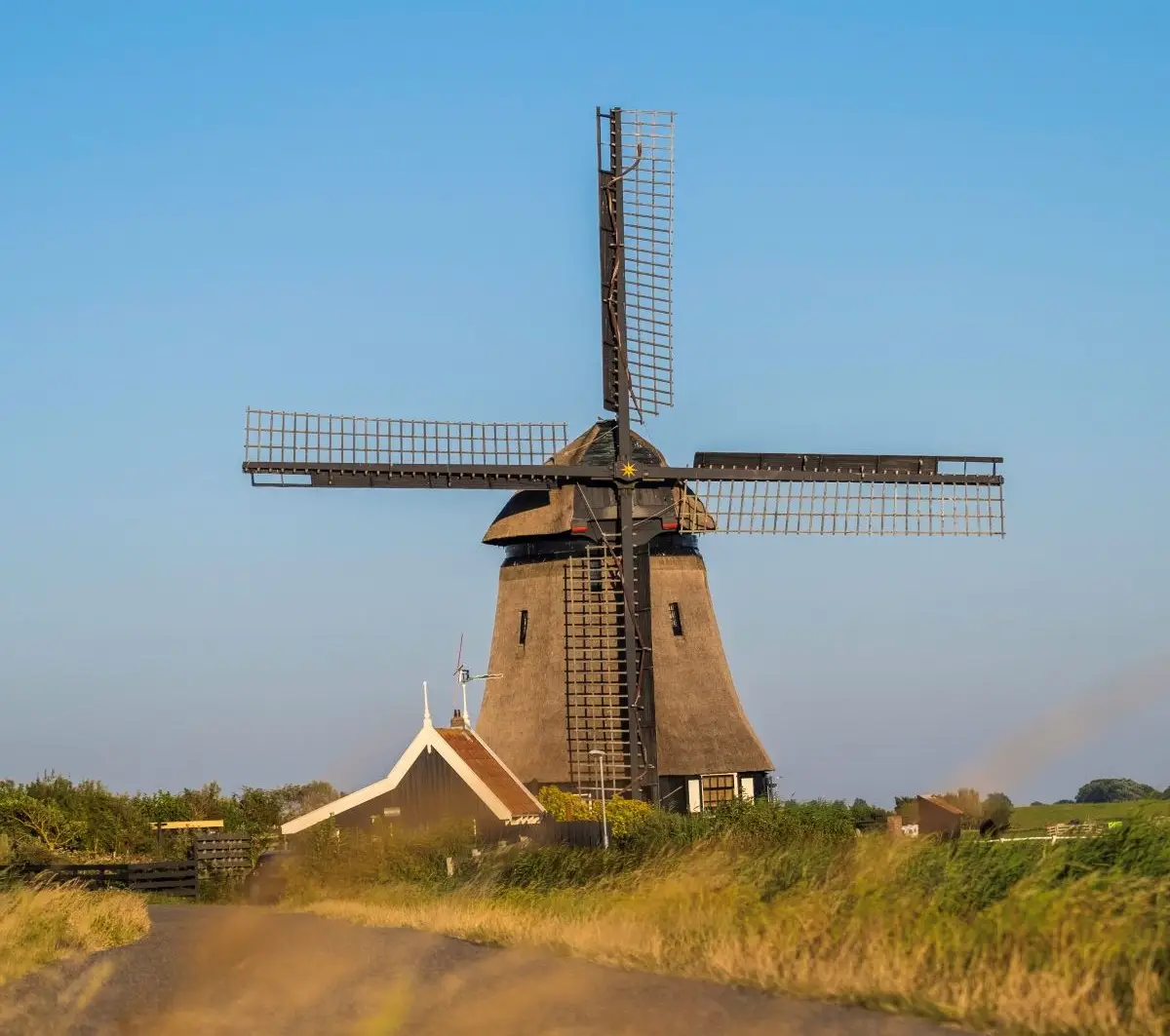 De Groetermolen in de polder met draaiende wieken op een mooie zomerse dag met blauwe lucht
