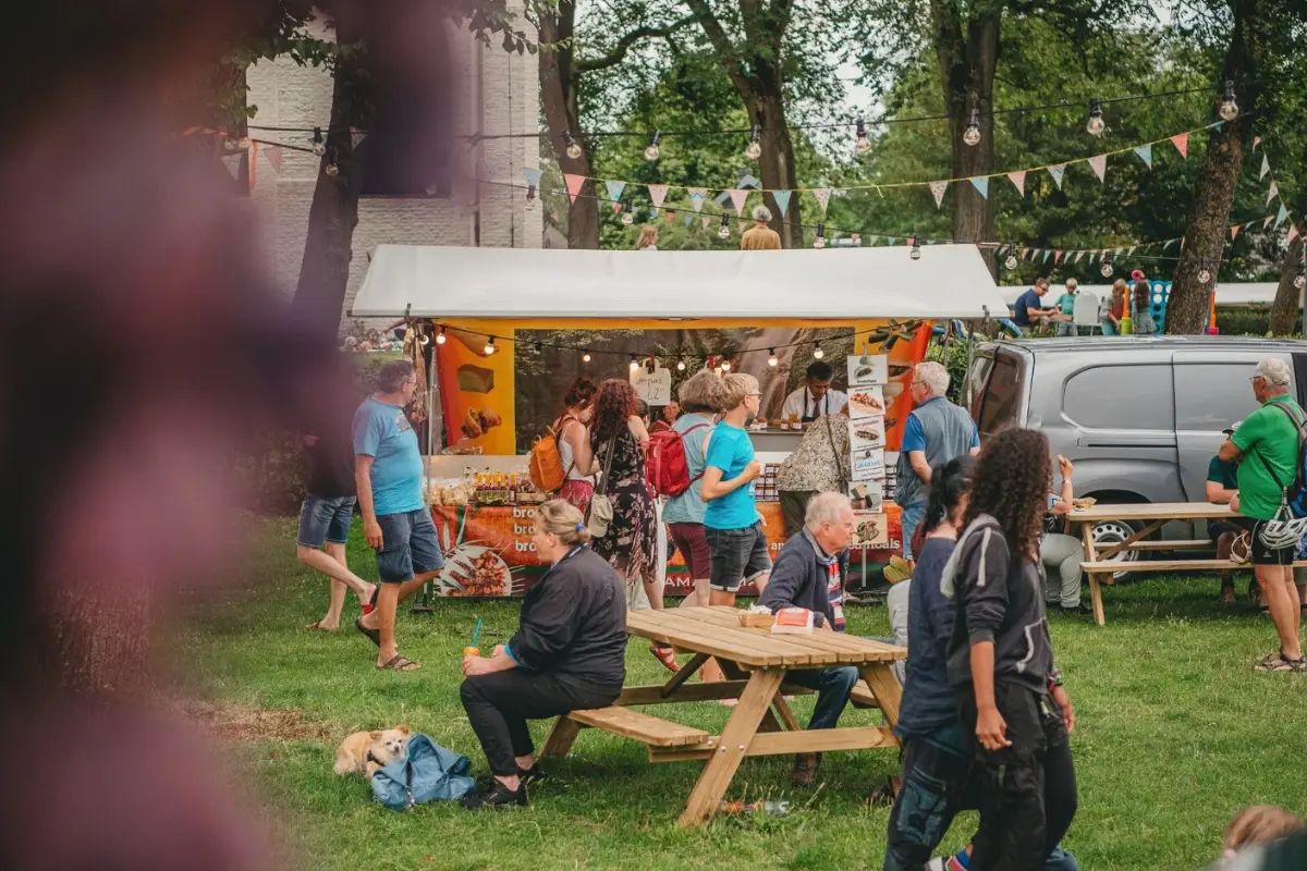 Marktkramen en slenterende mensen op ZomerGroet bij het Witte Kerkje in Groet