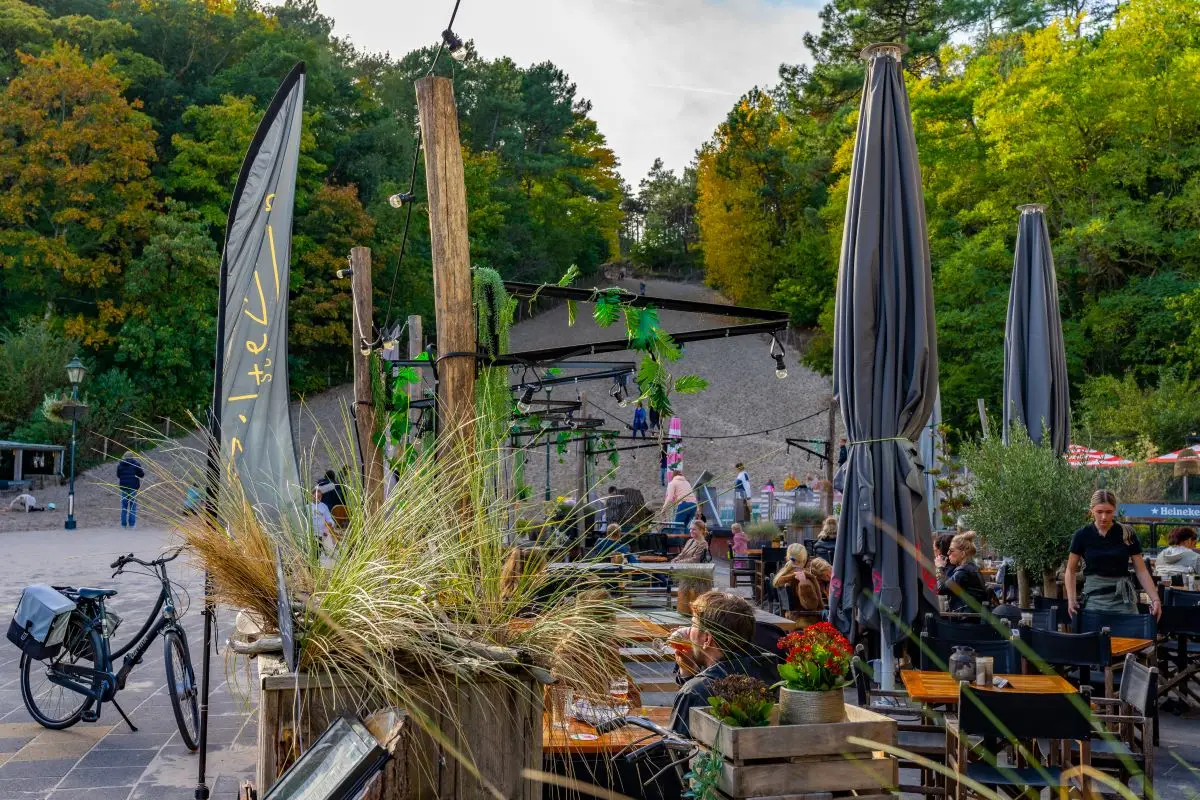 Drukgevuld terras bij het Klimduin met parasols, tafels en stoelen