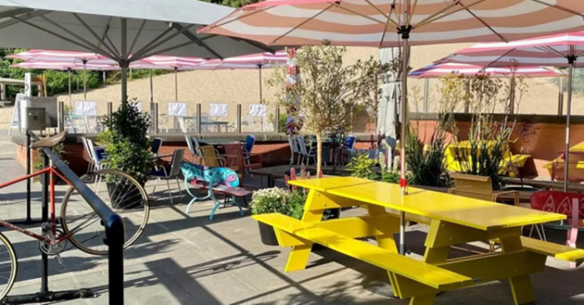 Terras bij JOOP met gekleurde parasols en een gele picknickbank