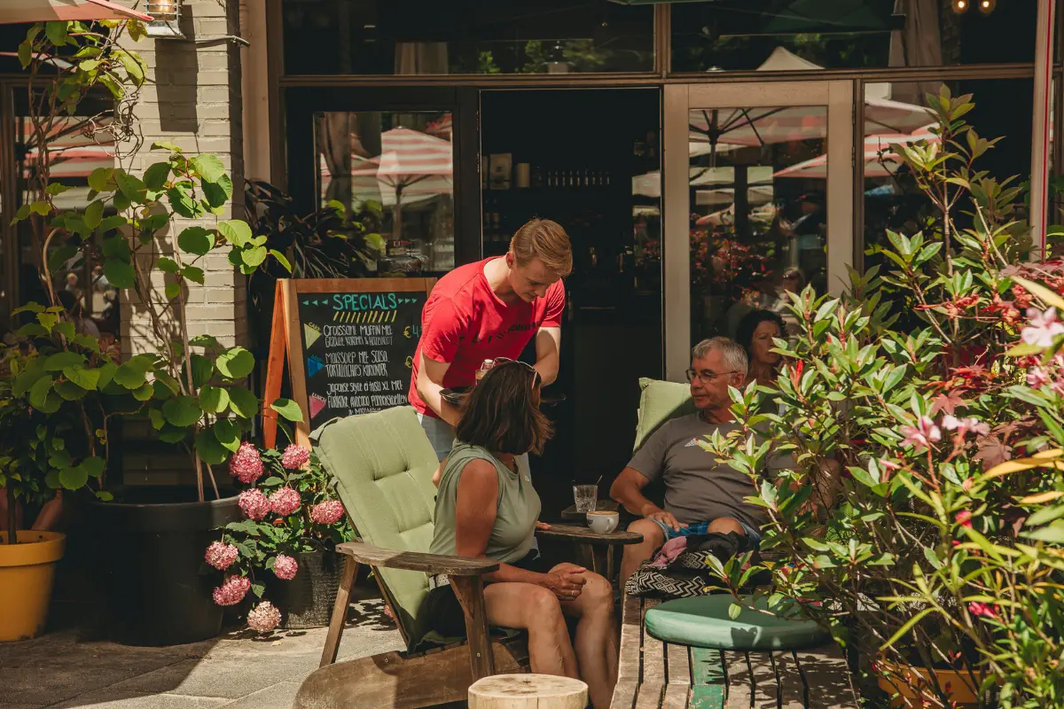 Terras bij JOOP met gekleurde parasols en een gele picknickbank