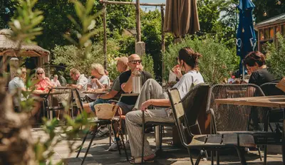 Mensen zitten op een zonnig terras tussen het groen, eten en drinken terwijl ze ontspannen samen genieten.