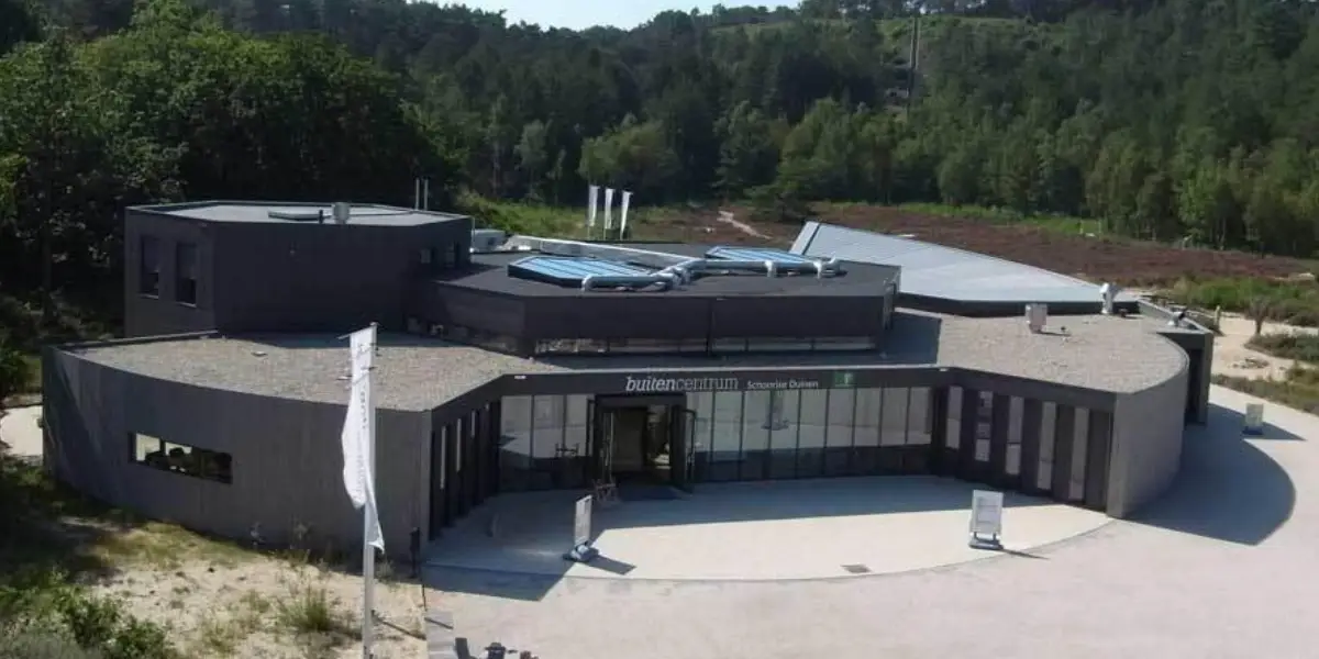 Bovenaanzicht van Buitencentrum Schoorlse Duinen, een grijs, groot gebouw tussen het duingebied