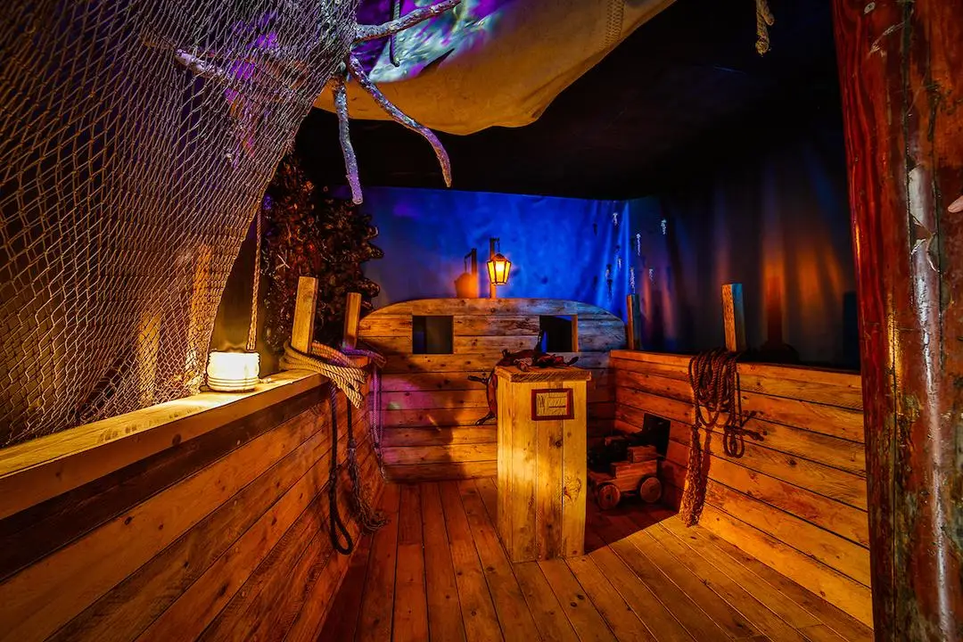 Foto van de escape room met vanbinnen de sfeer van een oud schip, met hout en visnettouwen