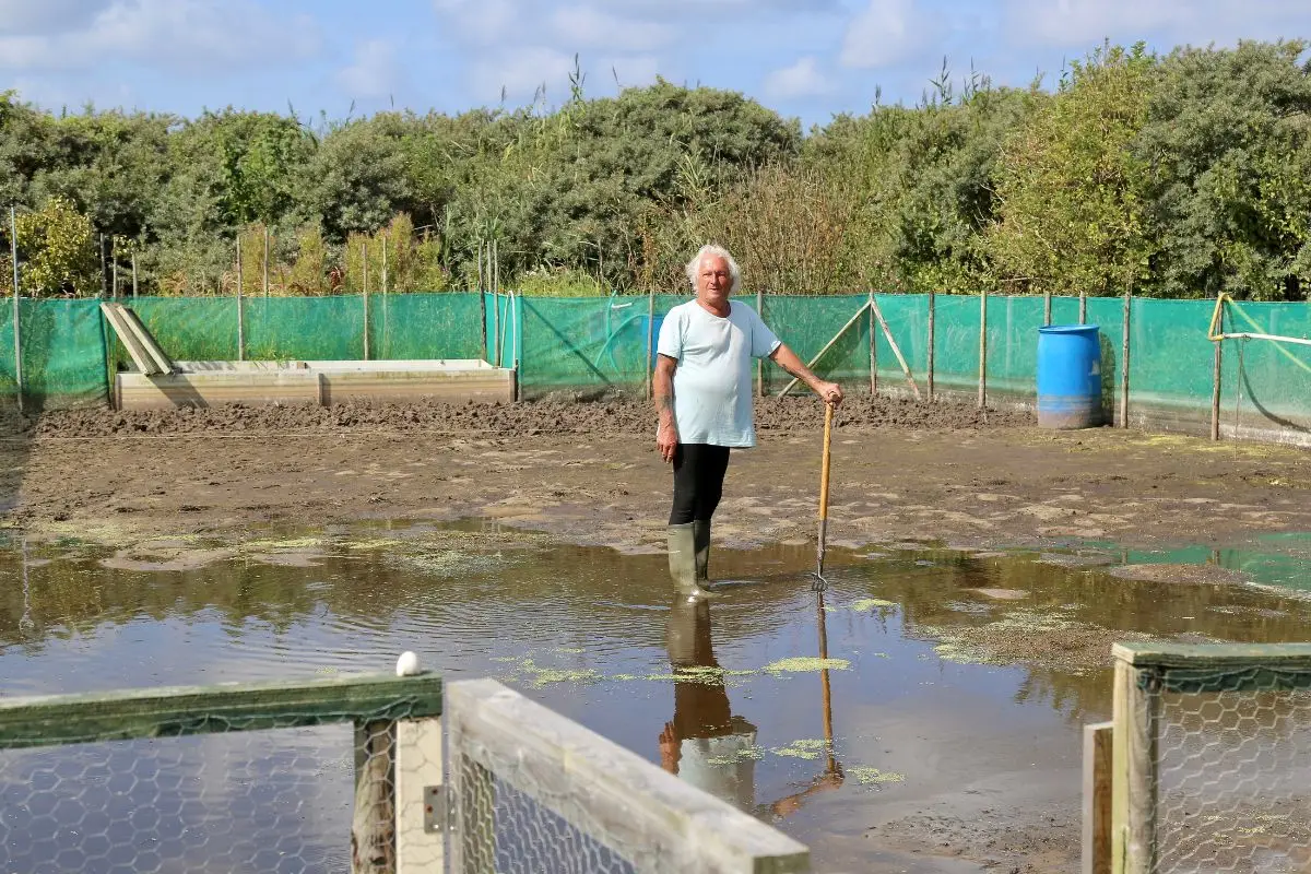 Man met schep staand in een akker onder het water