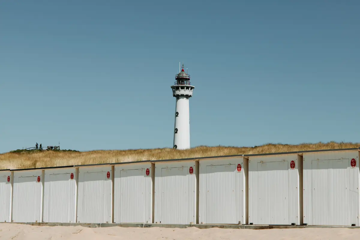 Witte vuurtoren van J.C.J. Speijk in Egmond aan Zee op een zonnige dag met blauwe lucht en de duinen met groen duingras