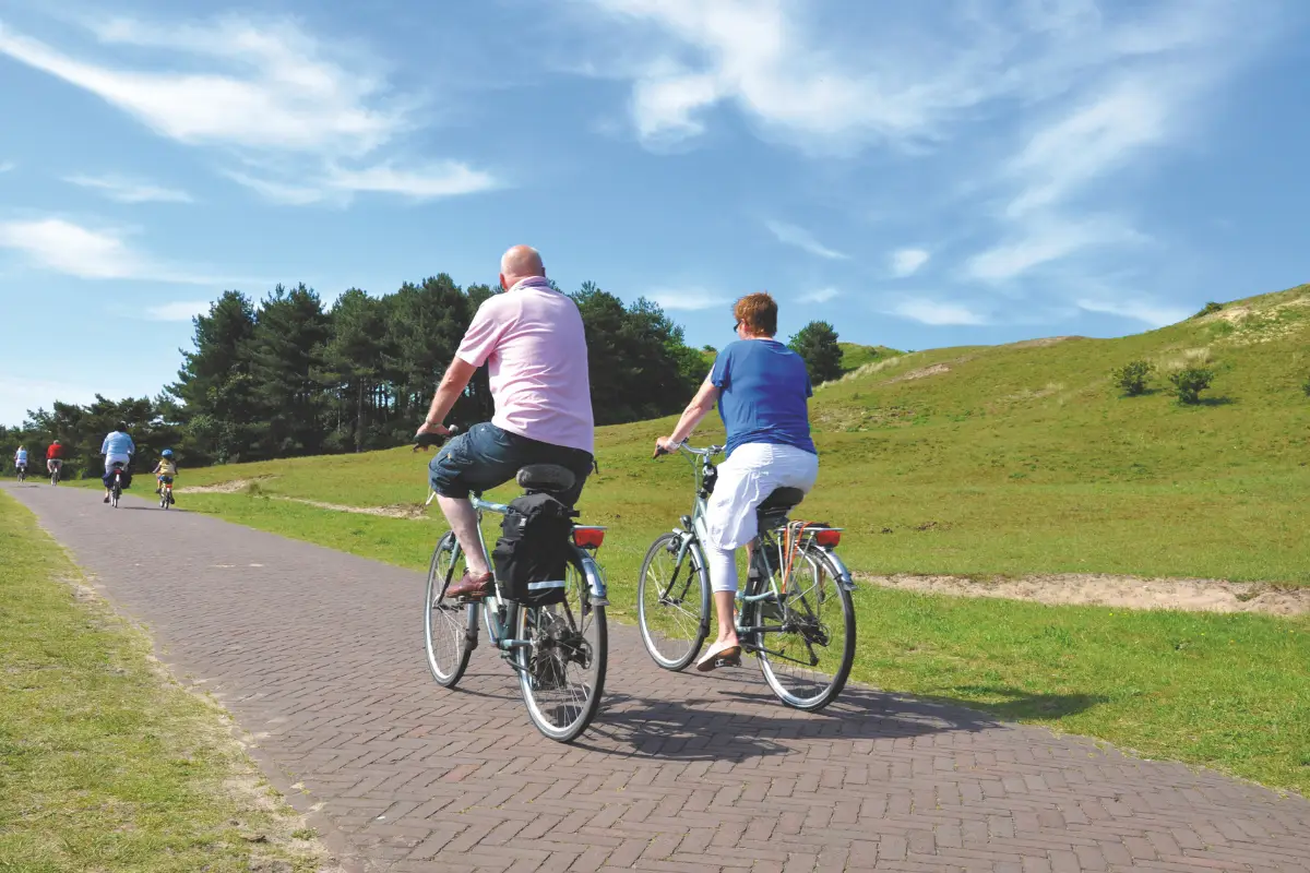 Wielrenners fietsen over een verhard pad door de bossen