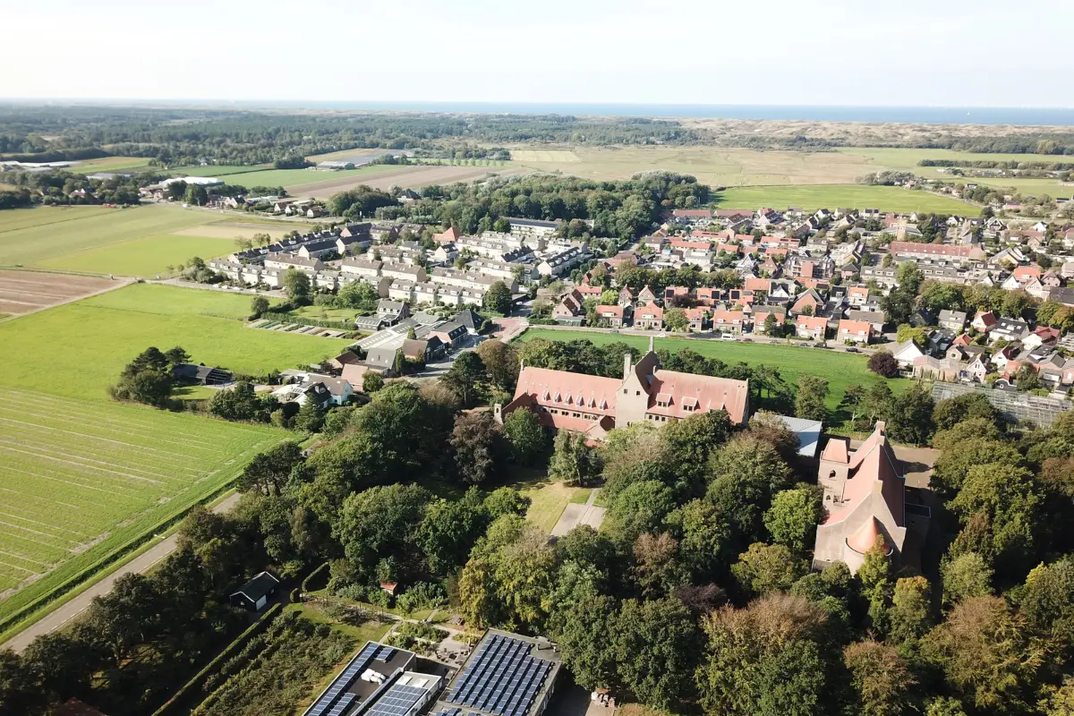 Luchtfoto van de Abdij van Egmond en het dorp Egmond-Binnen met in de verte de duinen, bossen en de zee
