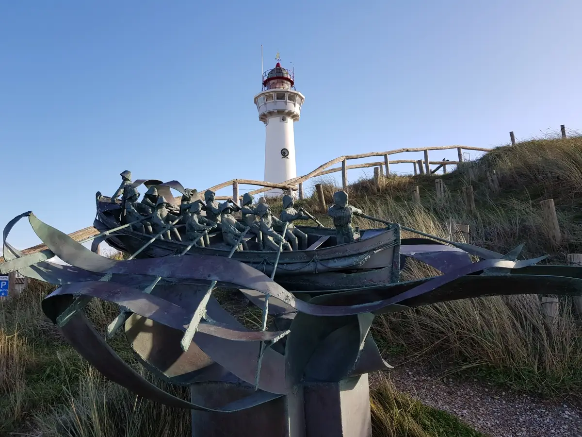 Beeld van roeireddingboot gemaakt door Loek van Meurs met op de achtergrond vuurtoren Van Speijk