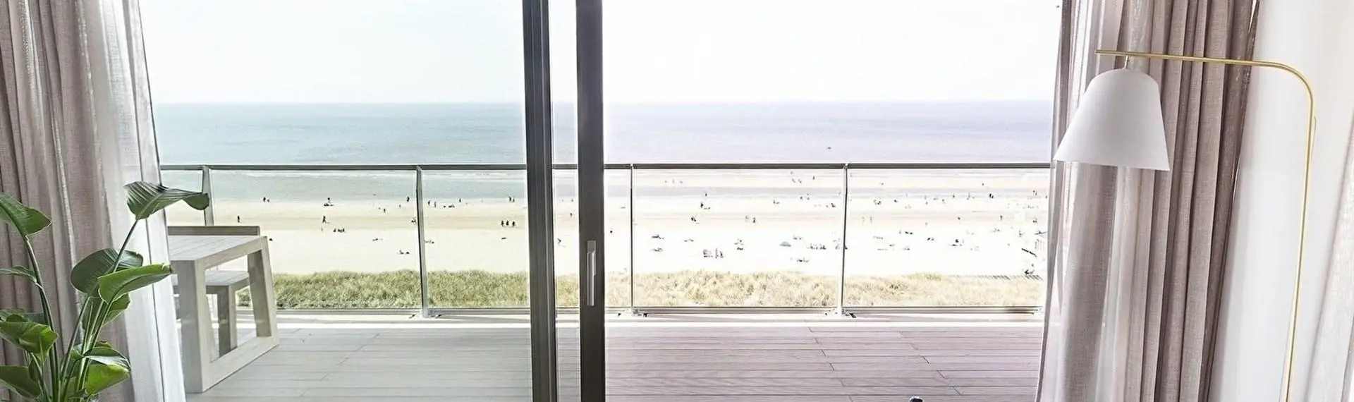 Zicht vanuit appartement op strand en zee op een zonnige dag