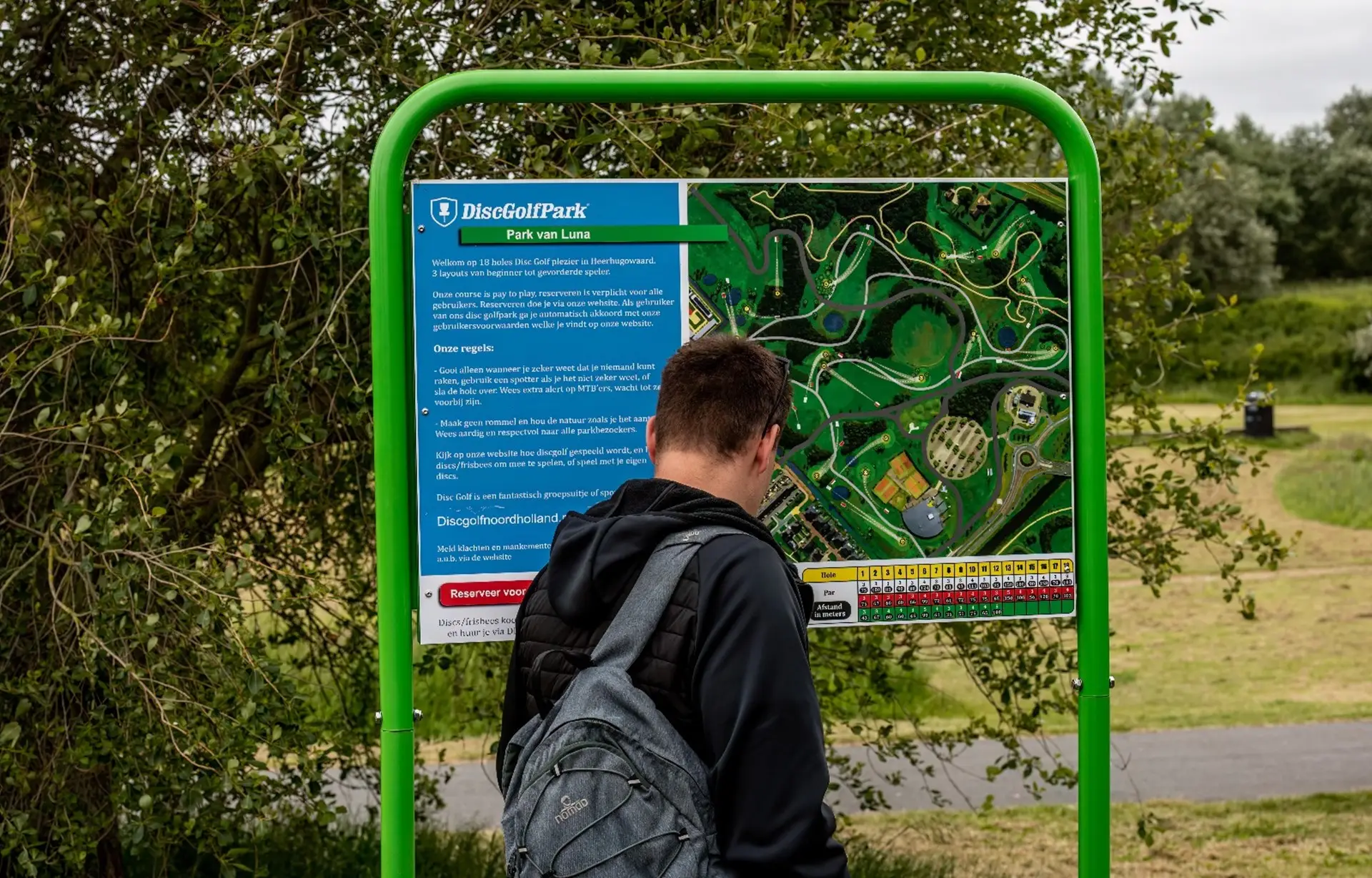 Meneer bij het Discgolf bord van Park van Luna
