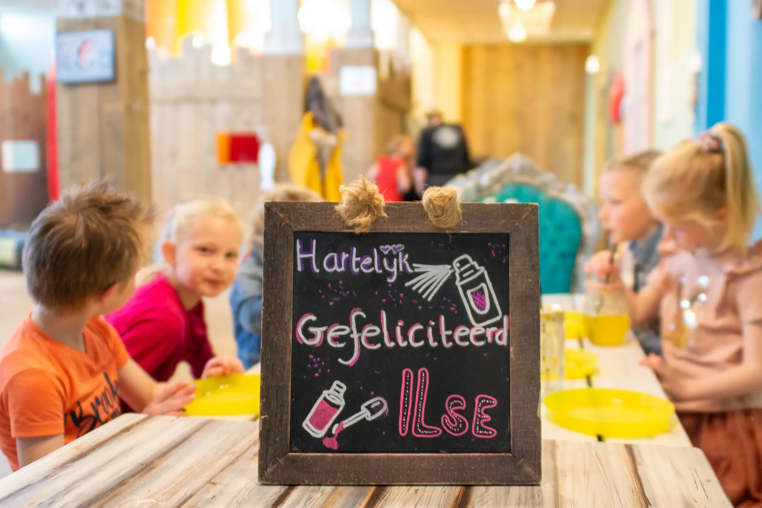 Bordje met hartelijk gefeliciteerd Ilse, bij Tante Suus op tafel.