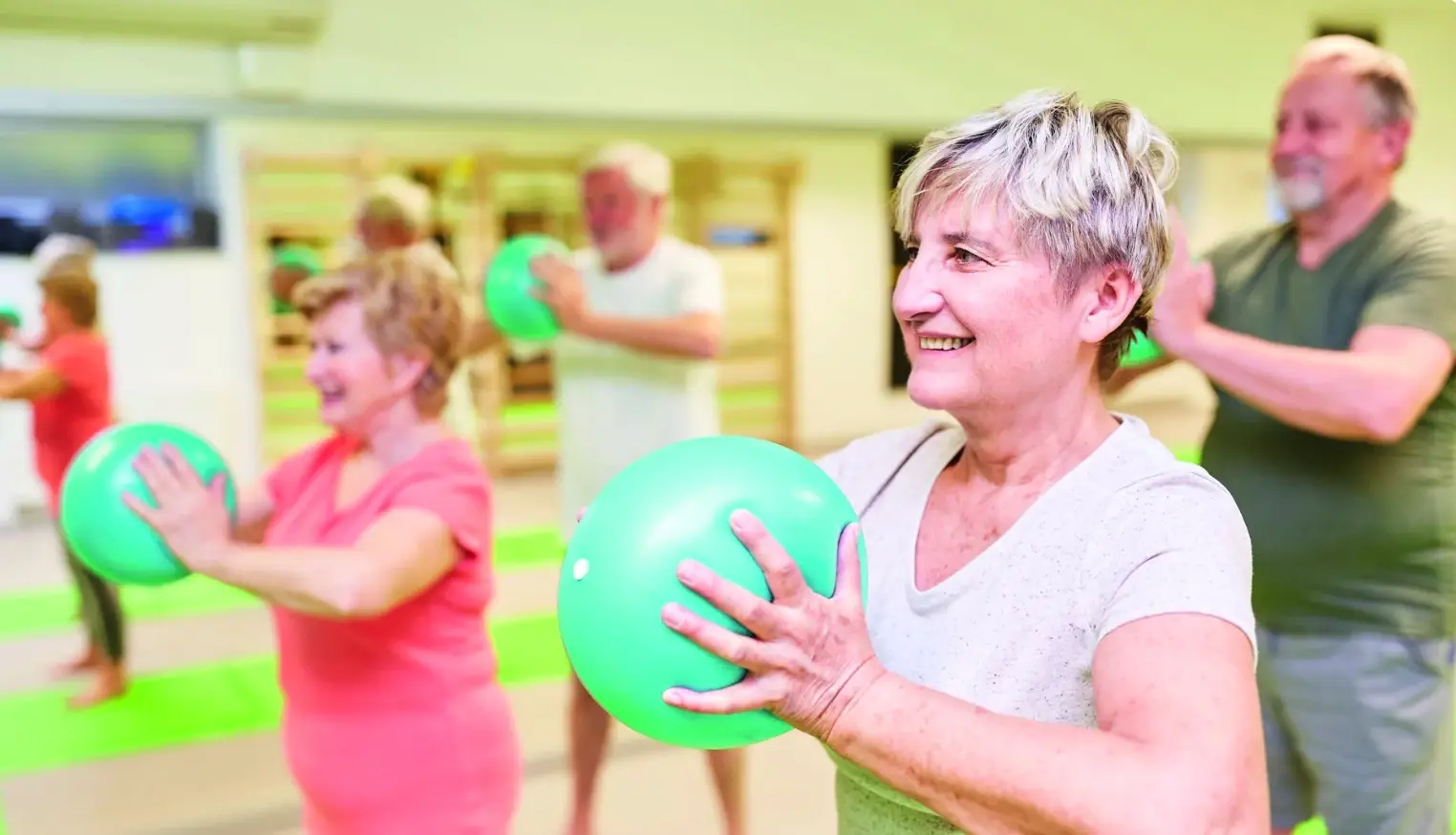 Senioren aan het sporten met een groene bal in de handen