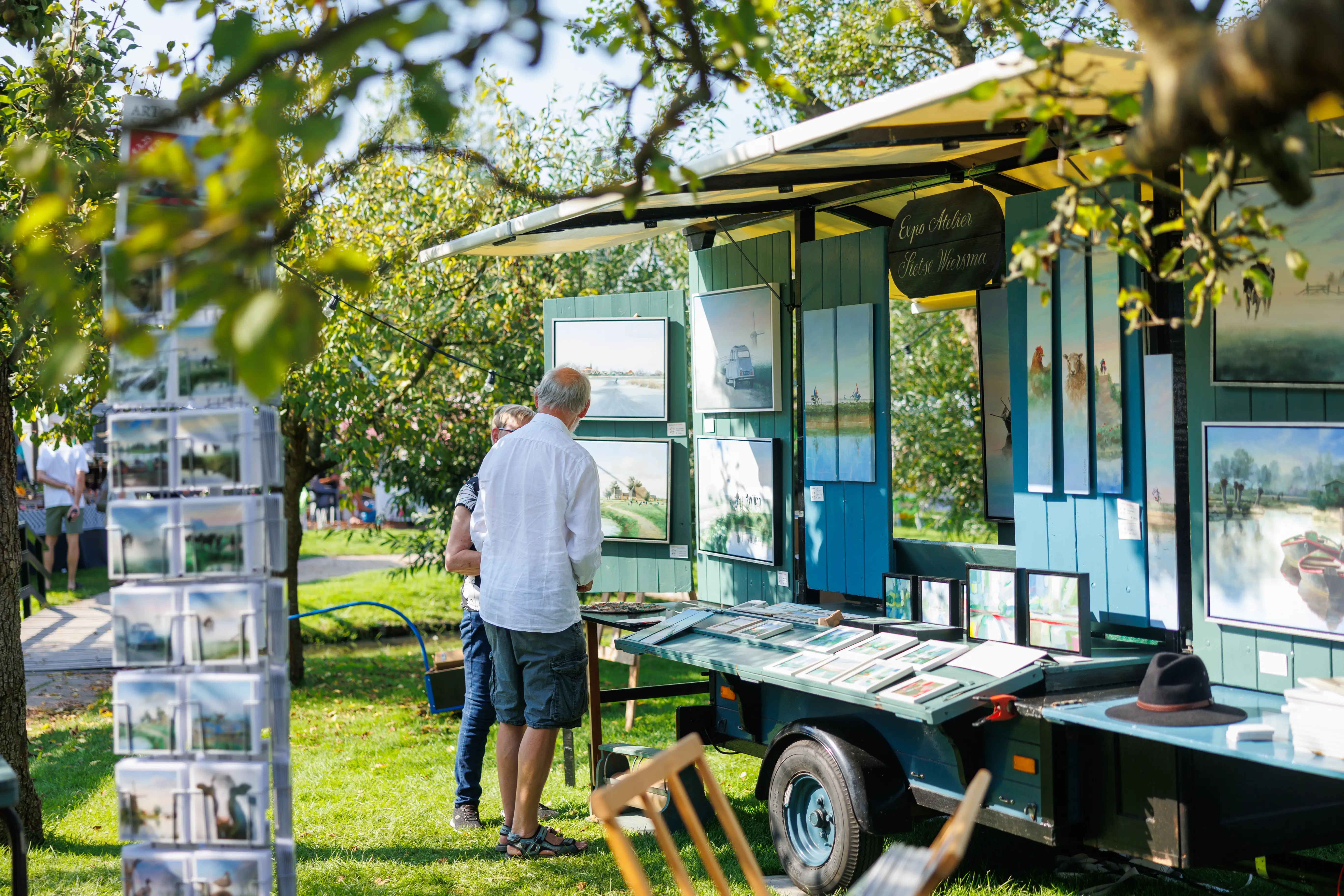 Schilder bij zijn schilderijen op de streekmarkt