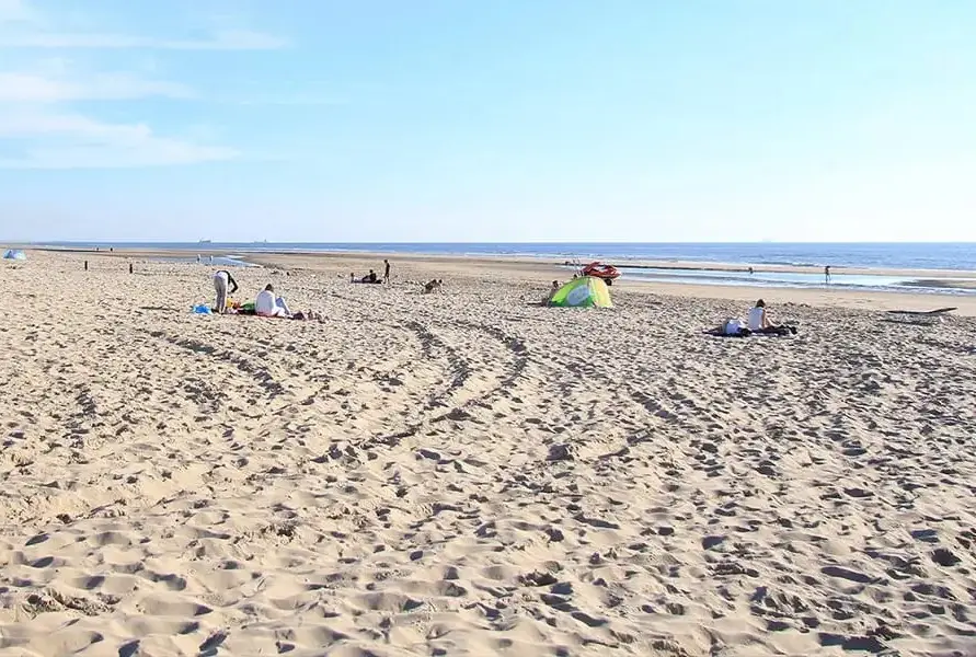 Mensen zitten op het strand bij castricum