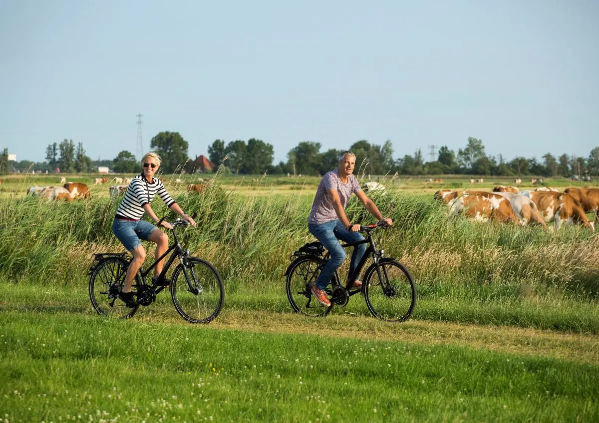 Man en vrouw op de fiets door het weiland