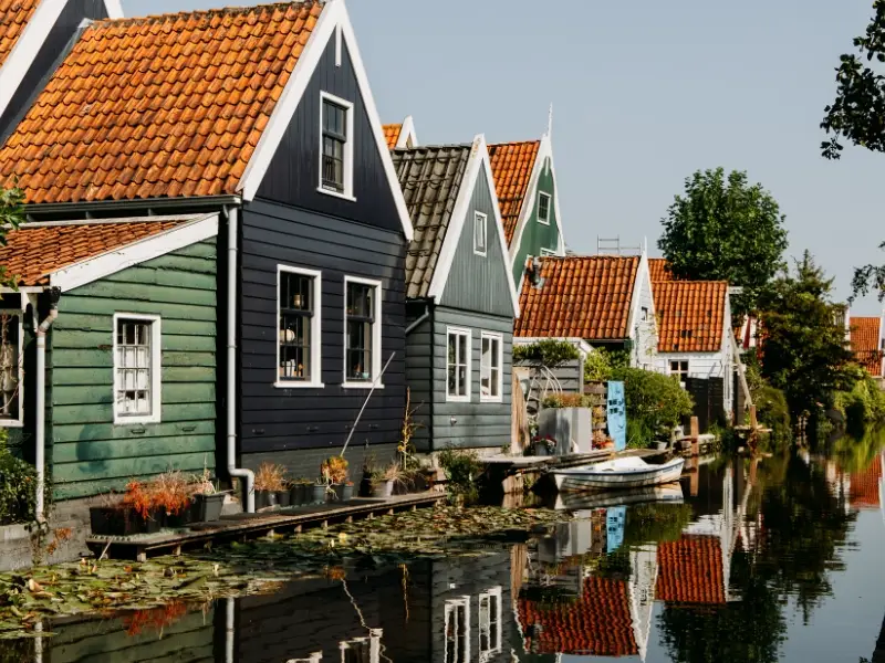 Karakteristieke houten huizen met rode dakpannen langs het water in De Rijp, met reflecties in het kanaal.